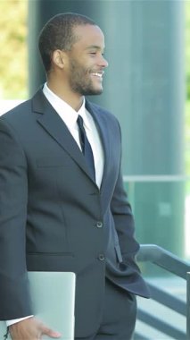 İki gülümseyen iş adamı canlı bir sohbete dalarken canlı bir karşılaşma gerçekleşir. Keskin elbiselerine güven yayarlar. Modern mimarinin gösterişli arkaplanı işbirliği ve başarı atmosferini güçlendirir, heyecanı yakalar.