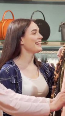 Modayı takip eden iki genç kadın canlı bir giyim mağazasında heyecanlı bir şekilde geziniyor ve satıştaki göz alıcı elbiseleri tartışıyorlar. Işıl ışıl gülüşleri ve gevezelikleri bulaşıcı bir atmosfer yaratıyor, arkadaşlığın sevincini ve