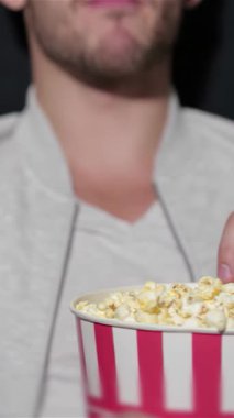 Neşeli bir çift büyük bir kova patlamış mısırı paylaşıyor, yüzleri sıcak bir sinemada yanıp sönen ekranla aydınlanıyor. Hava heyecan ve kahkahalarla doludur. Sinema deneyiminin tadını çıkarırlar. Çevrelerinde canlı film severler vardır.