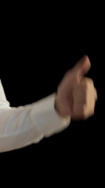 Gıcır gıcır beyaz gömlekli ve parlak siyah kravatlı şık bir beyaz adam çarpıcı bir siyah arka plana karşı cesur bir şekilde baş parmağını kaldırıyor. Bu dinamik görüntü, mesleki başarıyı sembolize ederek pozitiflik ve başarı yayar.