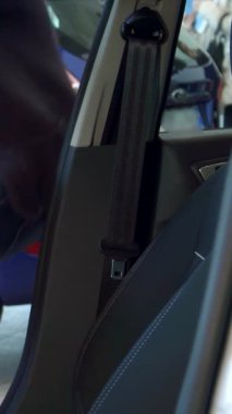 Şık, genç, bakımlı sakallı beyaz bir adam kemerini parlak, modern bir arabada takarken neşe saçıyor. Son model tasarım elementleriyle süslenmiş canlı iç mekan heyecan verici yeni sürüş yolculuğunun heyecanını arttırıyor.