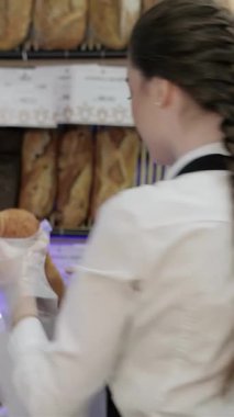 Gıcır gıcır beyaz bir gömlek ve önlükle giyinmiş neşeli genç bir fırıncı, sıcak bir kahve dükkanında yeni pişmiş altın bir somun sunar. Sıcak ortam, hamur işlerinin enfes kokusuyla zenginleşir. Müşterileri bir dizi hamur işinin tadını çıkarmaya davet eder.