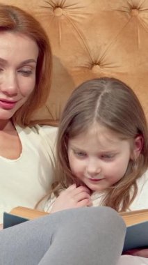 Hoş bir anne ve sevimli küçük kızı, kendilerini büyüleyici bir masal kitabının içine tıkıştırıp, rahat bir yatakta bir araya getirdikleri göz kamaştırıcı gülümsemelerini paylaşıyorlar. Yumuşak yatağın davetkar sıcaklığı ve yatak başlığının altın parıltısı huzur verir.