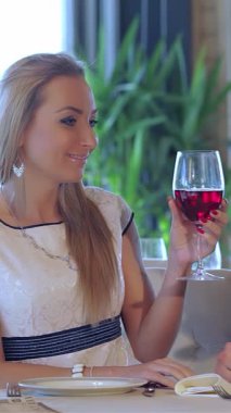 Lezzetli genç bir çift, şık bir restoranda yıl dönümlerini kutlayan kırmızı şarap kadehlerini paylaşıyor. Yumuşak ışık ve yemyeşil ile süslenmiş samimi ortam, sevgi ve neşe yayıyor, bu anı gerçek kılıyor.