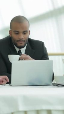 Sivri takım elbiseli dört neşeli genç işadamı, parlak bir masanın etrafında toplanır, tutkuyla fikir alışverişinde bulunurken kahve yudumlarlar. Doğal ışıkla yıkanan parlak, havadar ofis, bir işbirliği ve yenilik atmosferi yayıyor.