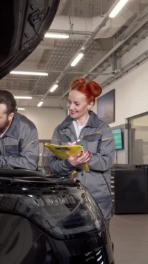 Modern bir garajda, odaklanmış bir adam ve özenli bir kadın, her ikisi de yetenekli tamirciler, parlak siyah bir otomobilin motorunu titizlikle inceliyorlar. Canlı kızıl saçlı kadın tamirci elinde bir not panosuyla hayati ayrıntıları yakalar.