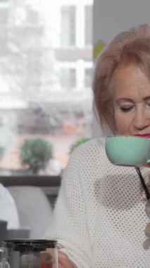 Büyüleyici bir kahve dükkanında, neşeli bir son sınıf öğrencisi orta yaşlı kızıyla keyifli bir çay anı paylaşır, yüzleri mutlulukla parlar. Kahkaha ve sıcaklıkla dolu samimi atmosfer, aile sevgisinin özünü güzel bir şekilde yakalar.