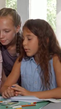 Coşkulu bir grup çocuk, etkileyici çizim becerilerinden büyülenmiş neşeli resim öğretmenlerinin etrafında toplanırken canlı bir sahne ortaya çıkıyor. Sıcak atmosfer yaratıcılık ve neşe ile doludur. Olgun bayan öğretmen ona ilham verir.