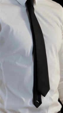 Kafkasyalı genç bir adam avuçlarını güvenli bir şekilde kavuşturarak güçlü bir onay ve başarı havası yayıyor. Gıcır gıcır beyaz gömleği ve keskin siyah kravatıyla profesyonelliği ve pozitifliği somutlaştırarak başarının özünü mükemmel bir şekilde yakalıyor.