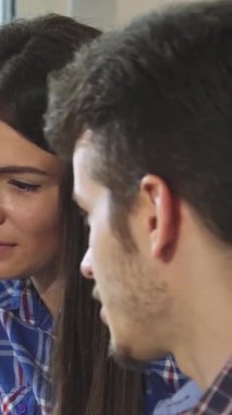 Bu canlı yakın çekim üç arkadaşın neşeli ifadeleri, sıcaklığı ve bağlantıyı yansıtan hareketli sohbetlerini gözler önüne seriyor. Kahve dükkanının davetkar atmosferi, yumuşak ışıklandırması ve şık dekoruyla, neşeyi arttırır.