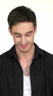 Parlak siyah gömlekli çekici bir genç adam düşünceli bir şekilde poz veriyor, nazik gülüşü yumuşak beyaz bir arka plana sıcaklık saçıyor. Elleri bağlı ve gövdesinde bir parça tıraş köpüğü ile, özgüveni ve modern tarzı somutlaştırıyor, izleyicileri davet ediyor.