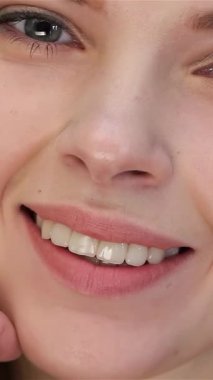 Kusursuz makyajı, kendine güveni ve zarafeti olan güzel beyaz bir kadının büyüleyici yakın çekimi. Parlak cildi, saf beyaz bir arka planda parıldıyor. Güzellik ve özgüven sanatını somutlaştırarak nazikçe yüzünü okşuyor.