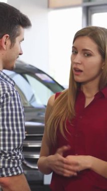 Canlı kırmızı bluzlu şık genç bir kadın galeride parıldayan otomobillerle çevrili erkek arkadaşıyla canlı bir tartışmaya girer. Aşikar heyecanları ve paylaşılan gelecek macera rüyaları keşfederken ışıldıyor.