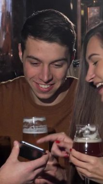 Neşeli bir üçlü arkadaş, iki erkek ve bir kadın, hareketli bir bira barında toplanır, içten kahkahalar atar ve akıllı telefonlarında eğlenceli bir şeyler keşfederler. Pub 'ların sıcak, cezbedici havası renkli içecekleriyle eşleştirildiğinde...