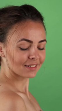 Işıl ışıl genç bir kadın zarif yeşil renkli bir arka plana karşı zarif bir şekilde poz verirken güzelliğini ve zarafetini sergiliyor. Büyüleyici gülüşü ve dengeli tavırları hayranlığı davet ediyor, kadınlığın ve kendine güvenin özünü kutluyor.