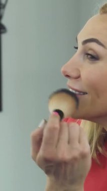 Parlak salonunu aydınlatan kendine güvenen gülüşü ve fırçayla makyaj yapan neşeli, olgun bir kadının yakın çekimi. Zarif güzellik aletleriyle çevrelenmiş sahne kadınsılık ve cazibe yayıyor, izleyicileri onun şık güzellik rutinine davet ediyor.