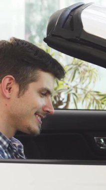 Neşeli bir genç adam, ışıl ışıl gülüyor. Lüks, üstü açılır bir arabada rahatça oturuyor. Heyecan ve tarz saçıyor. Satıcının modern zarafetiyle çevrelenmiş, direksiyonu kavrıyor, yeni maceralarına atılmaya hazır.