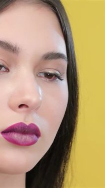 Yakın plan çekimde yetenekli bir vizörcünün göz kalemini göz kamaştırıcı bir Asyalı modelin gözüne ustalıkla sürerek zarif özelliklerini vurguladığı görülüyor. Parlak sarı arka plan enerji yayıyor, sanatsal ve titiz makyaj hassasiyetini vurguluyor.