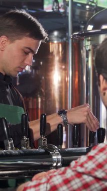 Parlak siyah gömlekli ve canlı yeşil önlüklü neşeli bir erkek barmen ustalıkla köpüklü birasını bardağa doldurur ve hevesli müşterisini memnun eder. Parıldayan bakır tanklarıyla, hareketli barın sıcak, davetkar atmosferi