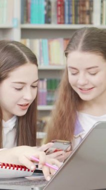 Uzun kahverengi saçlı kendini adamış bir liseli kız, renkli kitaplarla dolu canlı bir kütüphanede arkadaşlarıyla iş birliği içinde. Hareketli atmosfer, fikirleri paylaştıkça takım çalışması ve arkadaşlıkla uğulduyor.