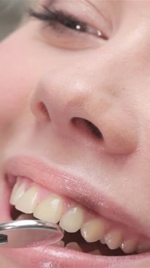 Kendini işine adamış bir dişçi dingin sarışın bir kadının üst kesici dişlerini titizlikle inceler. Parlak gülümsemesi güven yayar. Pırıl pırıl diş aletleri, yumuşak ışığı yansıtan, el değmemiş klinik ortam, profesyonelliğin ve özenin altını çiziyor.