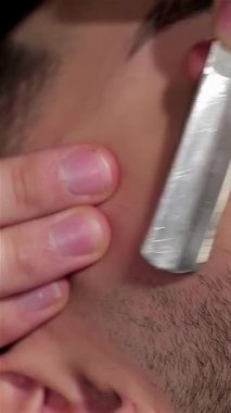 Şık bir adam kaliteli bir berber koltuğuna yaslanmış, yetenekli bir berber yanağında ustalıkla ustalıkla süzülerek incelik ve sanatını sergiliyor. Eski berber dükkanının sıcak, samimi atmosferi bu lüks tımar ritüelini geliştiriyor.