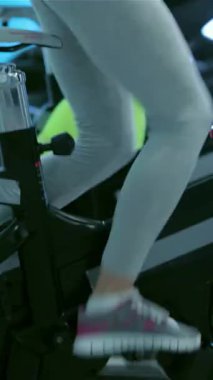 Güçlü bacakları olan atletik bir kız durağan bir bisikletin üzerinde enerjik bir şekilde pedal çeviriyor, fit arkadaşlarıyla çevrili, hepsi yüksek enerjili bir egzersize dalmış. Spor salonu motivasyon ve dostlukla dolup taşıyor. Sınırlarını zorluyorlar, güç gösterisi yapıyorlar.