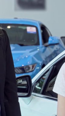 Hevesli bir bayan müşteri modern bir bayiden araba anahtarı alırken sevinçle ışıldıyor. Bu dinamik sahne, başarıyı simgeleyen parlak ve gösterişli araçların arka planına karşı yeni sahipliğin heyecanını yansıtıyor.