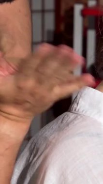 Neşeli bir kadın, geleneksel Tayland masajının rahatlatıcı kucaklamasının tadını çıkarıyor. Saf mutluluk saçan huzurlu ifadesi. Yetenekli masörlerin elleri ustalıkla sırtında süzülerek iyileştirici enerjiyle dolu huzurlu bir atmosfer yaratıyor.