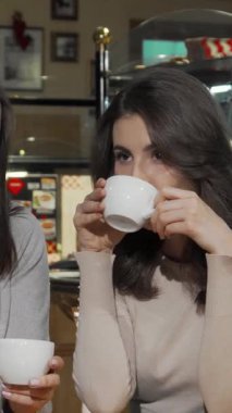 Neşeyle dolup taşan iki ışıl ışıl genç kadın büyüleyici bir kafede dumanı tüten kahve fincanlarıyla poz veriyor. Gülüşleri samimi atmosferi aydınlatıyor. Etrafları lezzetli hamur işleriyle ve sıcak bir atmosferle çevrili olarak, keyifli bir arkadaşlık anlarını paylaşıyorlar.