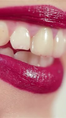 Bu büyüleyici yakın plan çekimde çarpıcı bir kadın cesur, canlı bir ruj sürüyor, ışıl ışıl gülüşü sahneyi aydınlatıyor. Görüntü kendine güven ve zarafet yayıyor, makyajın sanatını ve kendini ifade etmenin neşesini her şeyde kutluyor.