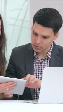 Dinamik genç bir iş adamı ve kadın, hem sıcaklık hem de coşku saçan parlak bir tabletteki verileri analiz ederken hareketli bir tartışmaya girişiyor. Doğal ışık ve şık dekorlarla dolu modern ofisleri, canlı bir atmosferi teşvik ediyor.