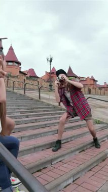 Üç genç arkadaş renkli açık hava basamaklarında neşeli bir şekilde poz verirken kahkahalarla gülmekten kırılıyorlar, yaz eğlencesinin özünü yakalıyorlar. Parlak gülümsemeleri ve gamsız jestleri neşe saçıyor, dostluk ve macera dolu canlı bir atmosfer yaratıyor.