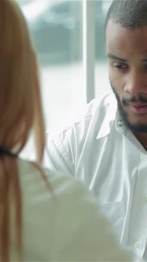 Parlak bir klinikte, şefkatli bir doktor genç bir adamı dikkatle dinler, destekleyici ve sıcak bir atmosferi teşvik eder. Boynuna bir steteskop sarılı olarak bir reçete yazarak, kendisini değerli ve anlaşılır hissetmesini sağlıyor.