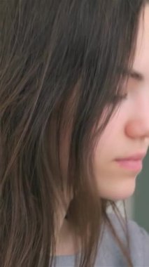 Uzun, dalgalı saçları olan, derin düşüncelere dalmış genç bir kadının yakın çekimi, iç gözlem ve kararlılığın bir karışımını gözler önüne seriyor. Yumuşak ışıklandırma onun özelliklerini vurgulayarak izleyicileri davet eden samimi bir atmosfer yaratıyor.