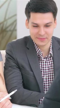 Tarz sahibi genç bir çift, güneşli modern bir ofiste bir iş analisti ile tutkuyla işbirliği yaparak, hevesle ve odakla fikir alışverişinde bulunuyor. Gösterişli kıyafetleri ve çağdaş çalışma alanları yaratıcı bir atmosfer yaratıyor.