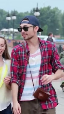 Üç şık genç arkadaş canlı bir şehir caddesinde gülüşmeler ve parlak güneşin altında gülüşmeler paylaşarak geziniyor. Canlı kıyafetleri ve kaygısız tavırları yaz eğlencesinin ve arkadaşlığın özünü somutlaştırarak unutulmaz anlar yaratıyor.