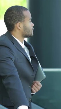 Dengeli bir Afrikalı işadamı, şık bir şehir zeminine karşı yeni ortakları sıcak bir şekilde karşılarken, tablet elinde güven içinde duruyor. Bu dinamik sahne, başarılı iş etkileşimlerinin ruhunu somutlaştıran profesyonellik ve fırsat yayıyor.