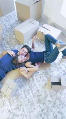 Kutularla dolu, güneşli, aydınlık bir odada, bir çift neşe ve heyecan dolu bir şekilde yerde yatıyor. Kahkahaları havayı dolduruyor, yeni evlerinde birlikte güzel bir yolculuğun başlangıcını simgeliyor.