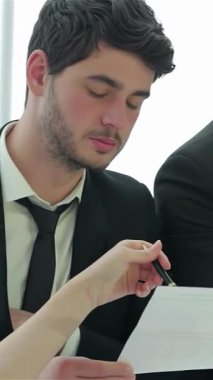 Üç keskin zekalı işadamı hayati belgeleri yoğun bir şekilde inceliyor. İfadeleri kararlılık ve hırsı yansıtıyor. Parlak, modern ofis kurulumu, başarı stratejileri üzerinde işbirliği yaparken enerji ile uğulduyor.