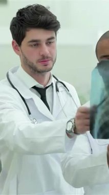 Pürüzsüz, modern bir klinikte, üç kendine güvenen doktor ve bir kadın, tıbbi uzmanlıklarını sergileyerek sağlıklı akciğerlerin röntgenini inceliyor. Odaklanmış ifadeleri ve beyaz önlükleri,