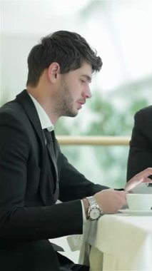 Keskin giyimli bir adam, tabletine derinden odaklanmış, modern iş dinamiklerinin özünü somutlaştırıyor. Kibar tavrı ve şık giyimi parlak, çağdaş bir ofis ortamında yenilik ve işbirliğine bağlılığını yansıtıyor.