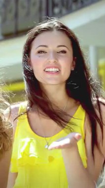 Mutluluktan patlayan üç şık genç kadın hareketli bir alışveriş bölgesinde neşeli öpücükler saçıyor canlı alışveriş torbaları sıcak güneş ışığında sallanıyor. Bulaşıcı gülüşleri ve ışıl ışıl gülüşleri...