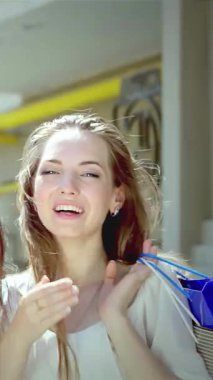 Zevkten dört köşe olmuş üç şık genç kadın canlı alışveriş bölgelerini keşfederken neşeli öpücükler saçıyorlar. Renkli alışveriş torbaları ellerinde sallanıyordu. Bulaşıcı gülüşleri ve ışıl ışıl gülüşleri, canlı bir dostluk ortamı yaratıyor.