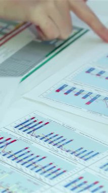 Canlı bir sahnede çeşitli eller aktif olarak iş belgelerindeki renkli grafik ve çizelgelere, somutlaştırıcı takım çalışması ve stratejik analizlere işaret ediyor. Bu büyüleyici görüntü, dinamik bir ofiste çalışan profesyonellerin sinerjisini vurgular.