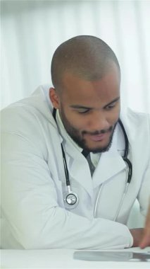 Crisp beyaz önlük ve steteskop giyen odaklanmış bir doktor bir hastayla göğüs röntgeni incelerken anlamlı bir tartışmaya girer. Parlak, modern klinik, sağlığın kritik önemini vurgulayarak profesyonellik ve güven yayıyor.