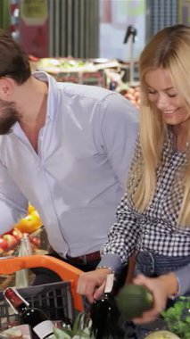 Neşeli genç bir çift, canlı sebzeleri taze sebzelerden oluşan bir kaleydoskopla çevrili, hareketli bir süpermarketten seçiyor. Yakışıklı beyaz adam, şık sakallı, gülümseyen sarışın kız arkadaşına olgun bir avokado veriyor.