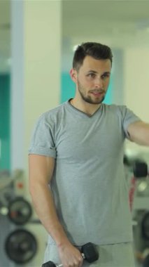 Ortadoğu kökenli kendini adamış genç bir adam triseps egzersizleriyle yoğun bir şekilde meşgul, parlak ve modern bir spor salonunda sarsılmadan dambılları kaldırıyor. Keskin fiziği ve kararlı ifadesi çevresi spor salonuyla çevrili.