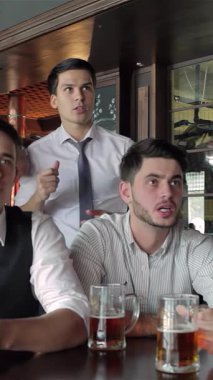 Dört şevkli iş adamı hareketli bir barda toplanarak, büyük ekranda heyecanlı bir futbol maçı izlerken coşkulu tezahüratlarla soğuk bardaklarını kaldırıyorlar. Titreşimli atmosfer kahkaha ve heyecanla uğulduyor.