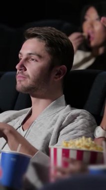 Bir grup arkadaş, samimi bir sinemada büyüleyici bir filme dalmış kahkahalar ve samimi anlar paylaşıyorlar. Renkli patlamış mısır kovaları ve ferahlatıcı içeceklerle, bu canlı sahne sinemanın neşesini ve sihrini yayıyor.